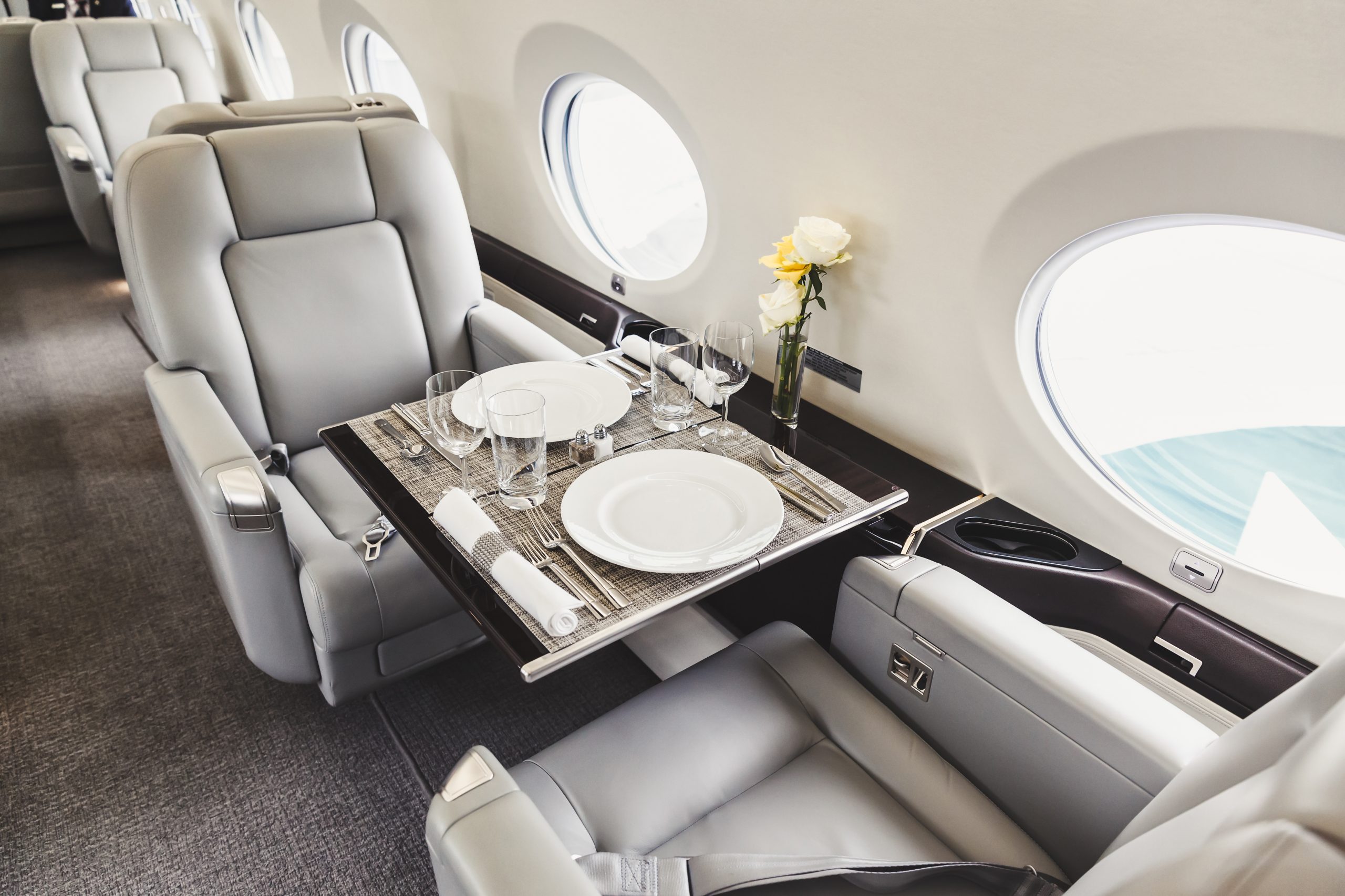 Luxury private jet interior with tray table and champagne — RYL Jets charter experience